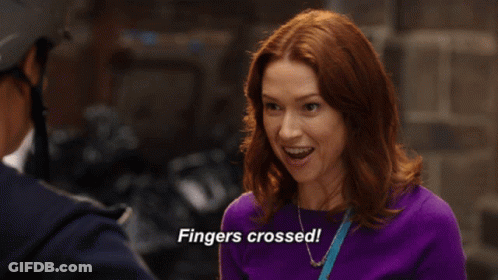 A Woman In A Purple Sweater Is Saying Fingers Crossed GIF