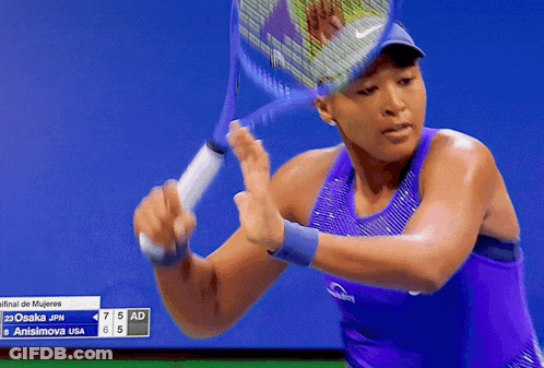 A Woman In A Purple Tank Top Holds A Tennis Racket GIF