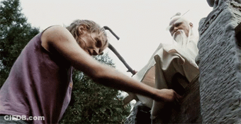 A Woman In A Purple Tank Top Is Reaching Out Towards A Statue GIF