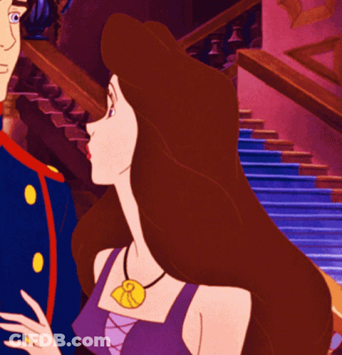 A Woman In A Purple Top Has A Necklace With A Pendant That Says R On It GIF