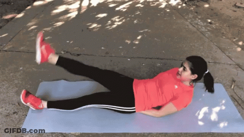 A Woman In A Red Adidas Shirt Is Laying On A Yoga Mat With Her Legs Crossed GIF