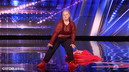 A Woman In A Red And Black Plaid Shirt Is Dancing On A Stage With A Blue Background . GIF