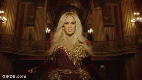 A Woman In A Red And Gold Dress Is Standing In A Room With Columns GIF
