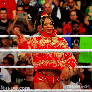 A Woman In A Red And Gold Outfit Is Standing In A Ring . GIF