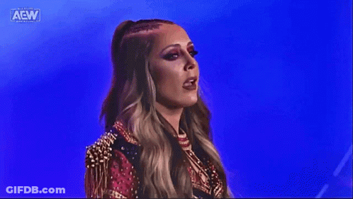 A Woman In A Red And Gold Outfit Is Standing In Front Of A Blue Background On A Stage . GIF