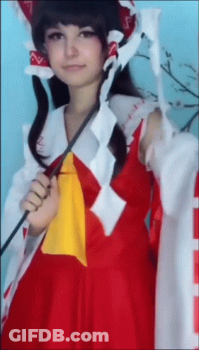 A Woman In A Red And White Costume Is Holding A Sword . GIF