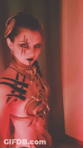 A Woman In A Red And White Costume With A Necklace Around Her Neck GIF