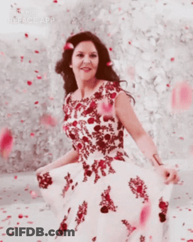 A Woman In A Red And White Dress Is Standing In Front Of A Wall GIF