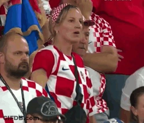 A Woman In A Red And White Nike Shirt Is Sitting In The Stands GIF