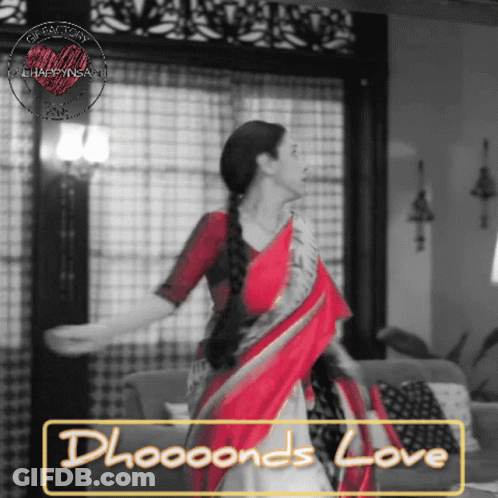 A Woman In A Red And White Saree Is Dancing In A Living Room GIF