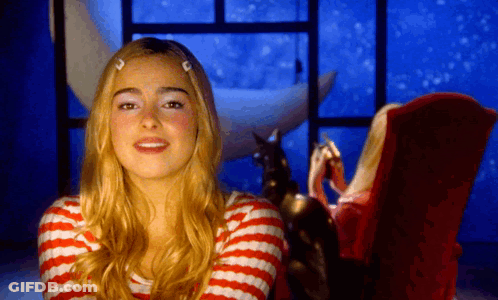 A Woman In A Red And White Striped Shirt Is Sitting In A Chair GIF