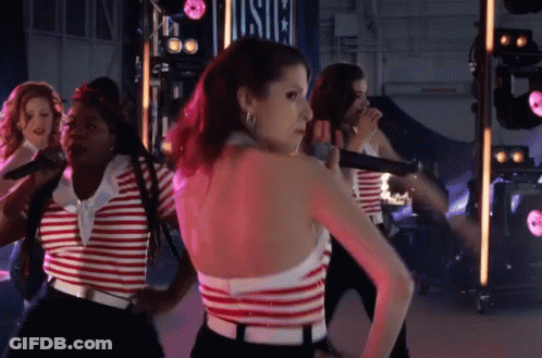 A Woman In A Red And White Striped Top Is Standing In Front Of A Sign That Says Usic GIF