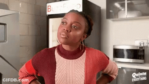 A Woman In A Red And White Sweater Is Standing In Front Of A Refrigerator . GIF