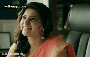A Woman In A Red And Yellow Saree Is Smiling While Sitting In A Car . GIF