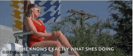 A Woman In A Red Bathing Suit Is Sitting In A Chair On A Deck . GIF