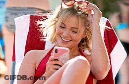 A Woman In A Red Bikini Is Sitting In A Chair Looking At Her Phone . GIF