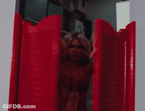 A Woman In A Red Bra Is Holding Up Her Arms In A Doorway GIF