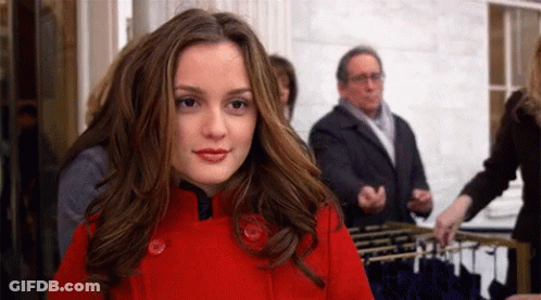 A Woman In A Red Coat Is Standing In Front Of A Display Of Clothes GIF