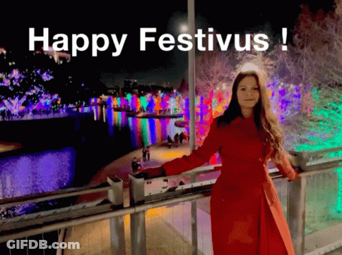 A Woman In A Red Coat Leaning On A Railing With The Words Happy Festivus Written Above Her GIF