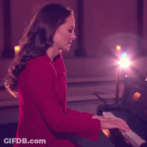 A Woman In A Red Coat Playing A Piano GIF