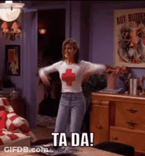 A Woman In A Red Cross Shirt Is Dancing In A Living Room With The Words Ta Da On The Bottom . GIF