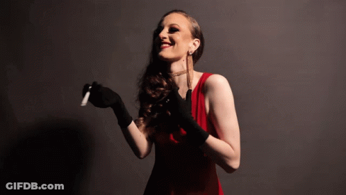 A Woman In A Red Dress And Black Gloves Is Holding A Cigarette GIF