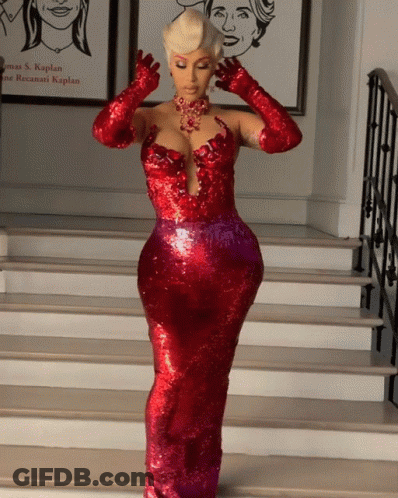 A Woman In A Red Dress And Gloves Stands On Stairs GIF