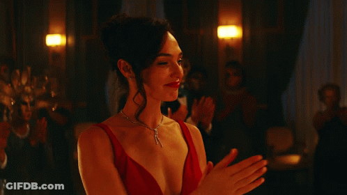 A Woman In A Red Dress And Necklace Is Clapping GIF