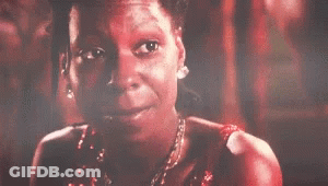 A Woman In A Red Dress And Necklace Is Smiling . GIF