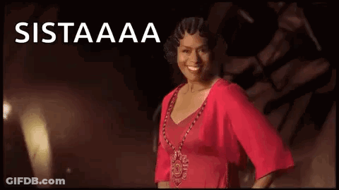 A Woman In A Red Dress And Necklace Is Smiling In Front Of A Black Background . GIF