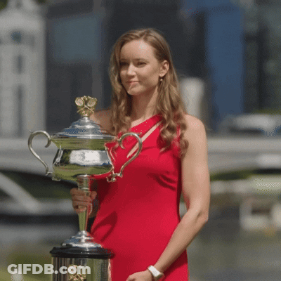 A Woman In A Red Dress Holding A Trophy GIF