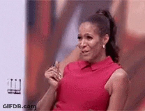 A Woman In A Red Dress Is Crying While Sitting In Front Of A Screen . GIF