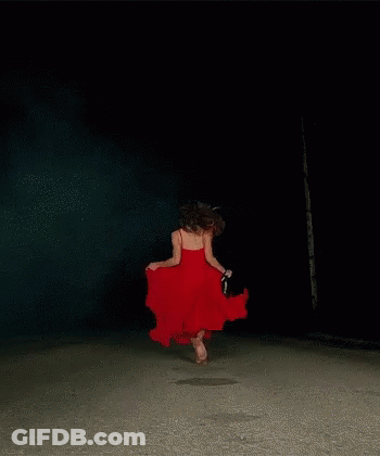 A Woman In A Red Dress Is Dancing Barefoot In The Dark GIF