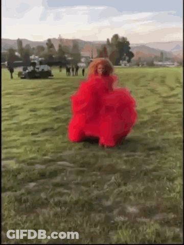 A Woman In A Red Dress Is Dancing In A Field . GIF