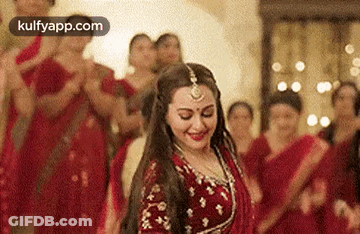 A Woman In A Red Dress Is Dancing In Front Of A Crowd Of People . GIF
