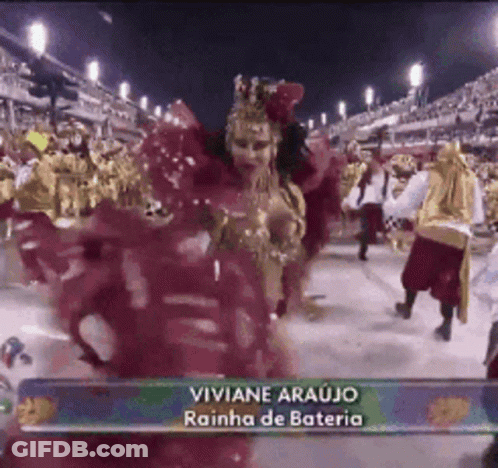 A Woman In A Red Dress Is Dancing In Front Of A Crowd With The Name Viviane Araujo On The Bottom Right GIF