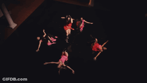 A Woman In A Red Dress Is Dancing In Front Of A Red Cloth GIF