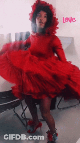 A Woman In A Red Dress Is Dancing In Front Of A Wall That Says Love GIF