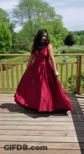 A Woman In A Red Dress Is Dancing On A Deck . GIF
