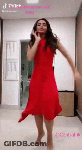 A Woman In A Red Dress Is Dancing On A Tiled Floor . GIF