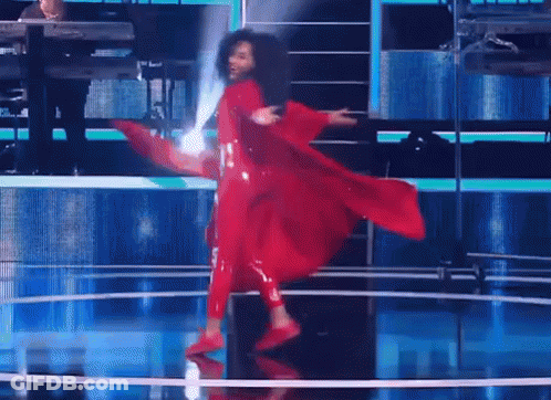 A Woman In A Red Dress Is Dancing On Stage GIF