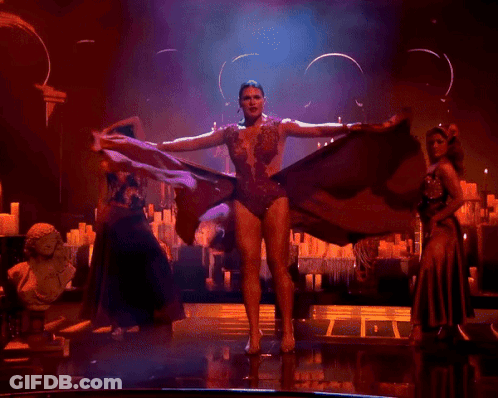 A Woman In A Red Dress Is Dancing On Stage GIF