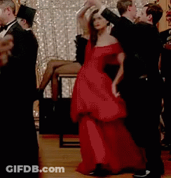 A Woman In A Red Dress Is Dancing With A Man In A Black Tuxedo . GIF