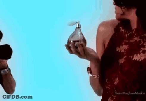 A Woman In A Red Dress Is Holding A Bottle Of Perfume In Her Hands GIF