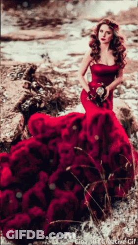 A Woman In A Red Dress Is Holding A Bouquet Of Red Roses GIF