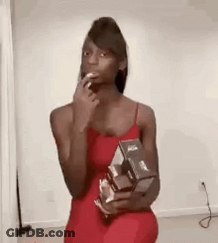 A Woman In A Red Dress Is Holding A Box Of Cereal And A Cigarette In Her Mouth . GIF