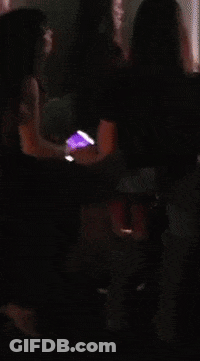 A Woman In A Red Dress Is Holding A Cell Phone In Her Hand GIF