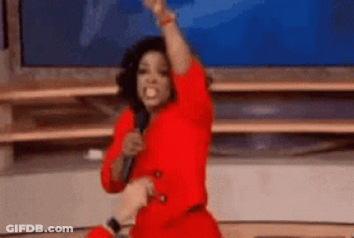A Woman In A Red Dress Is Holding A Microphone And Raising Her Fist . GIF