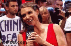 A Woman In A Red Dress Is Holding A Microphone And Smiling In Front Of A Crowd . GIF