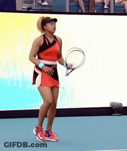 A Woman In A Red Dress Is Holding A Tennis Racket On A Tennis Court . GIF